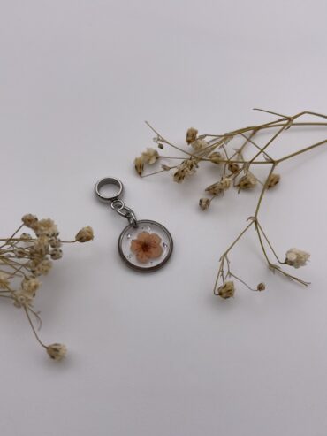 Charm redondo con flor naranja y pisquitos plateados