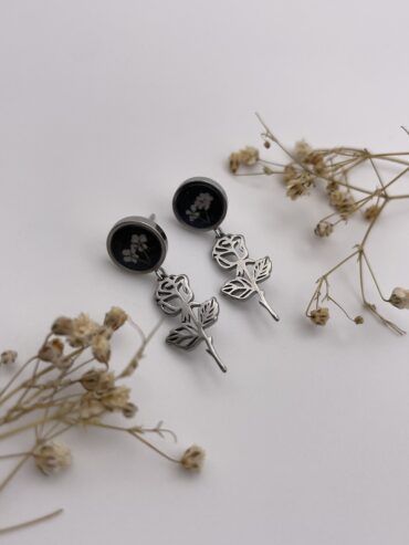 Pendientes redondos en color negro con florecitas blancas y charm de rosa